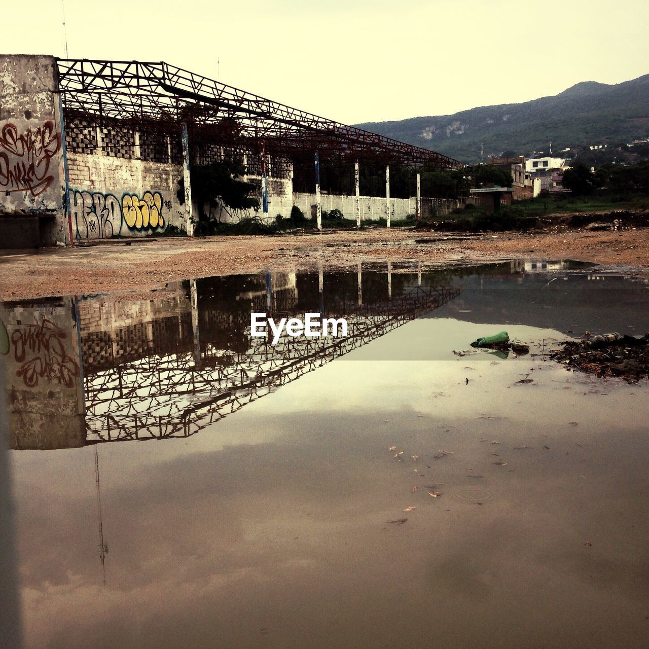 Puddle by abandoned building against clear sky