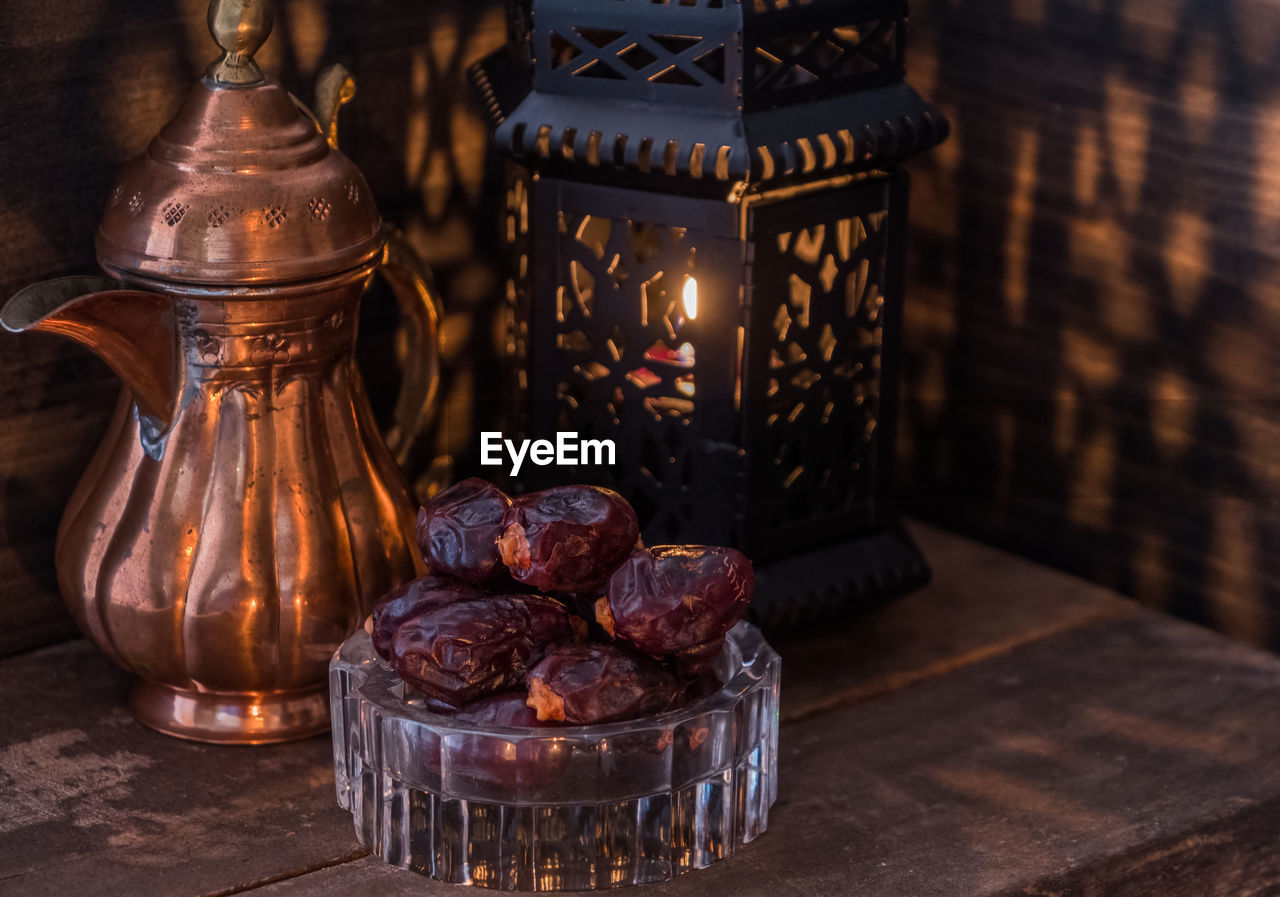 Close-up of antique teapot and lantern with raisins on table