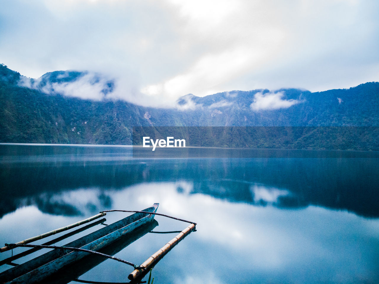 Scenic view of lake by mountains against cloudy sky