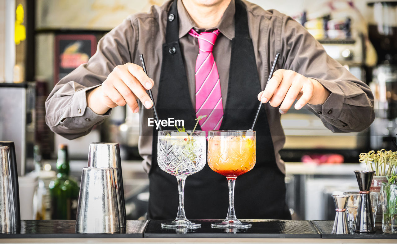 Midsection of bartender preparing drink at counter