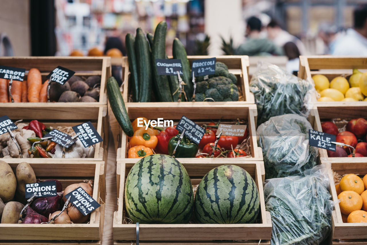 Variety of fresh fruit and vegetables in wooden crates, on sale at a market.