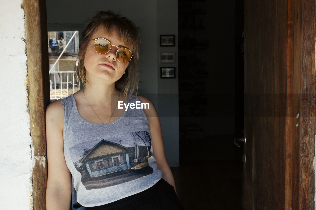 Portrait of young woman standing on entrance