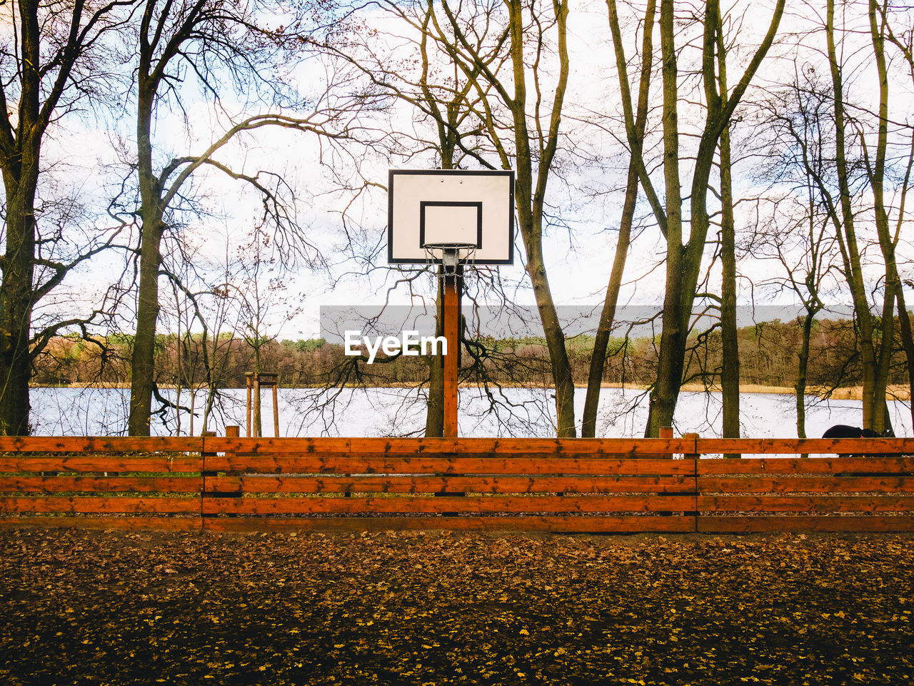 Basketball hoop in park against lake during winter