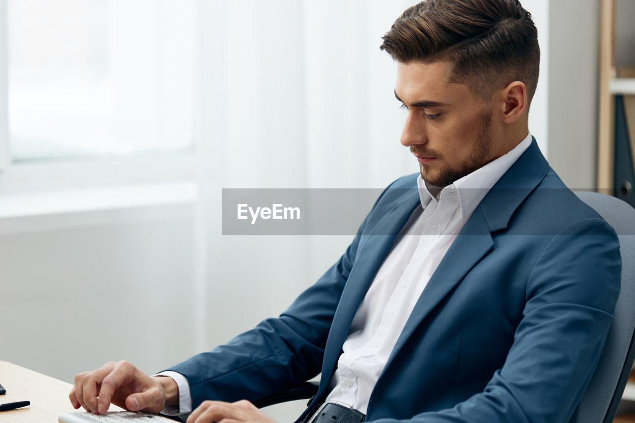 Young businessman sitting by desk at office