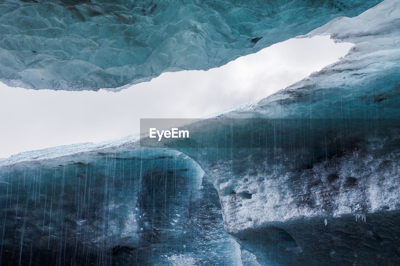 Clean water falling from fragile transparent icicles inside ice cave in vatnajokull glacier in iceland