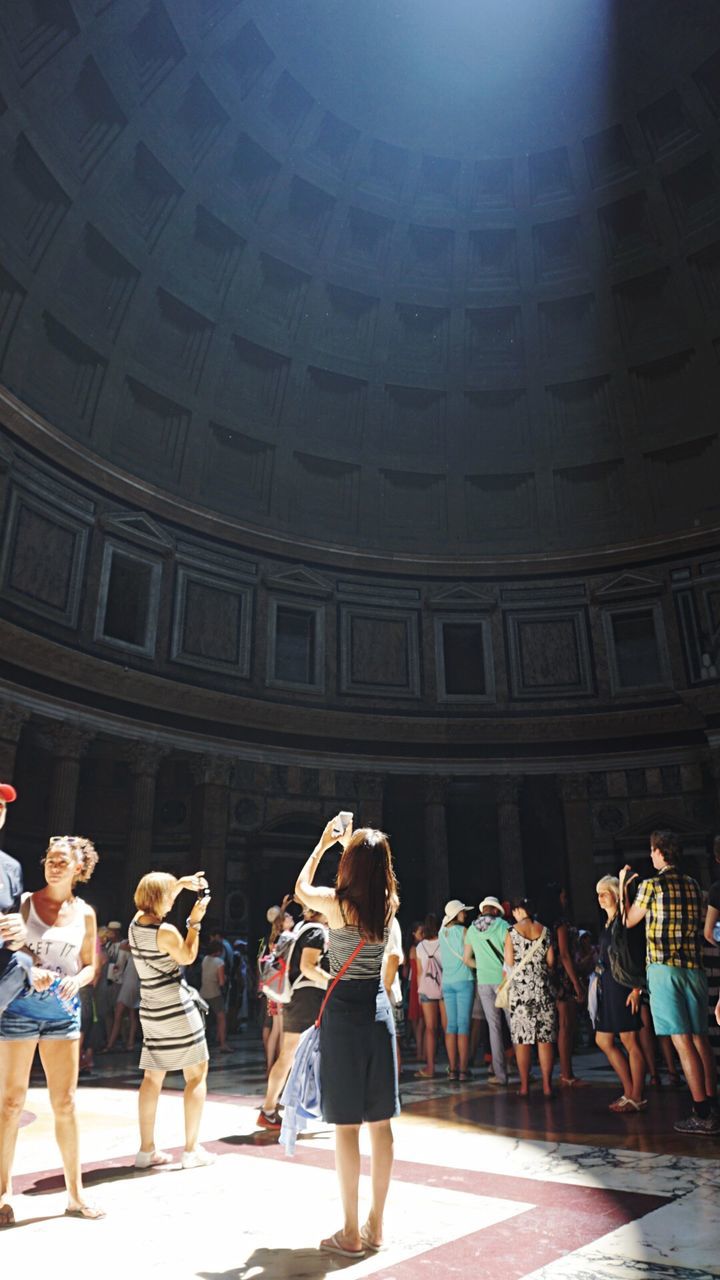 Rear view of young woman taking picture of ceiling