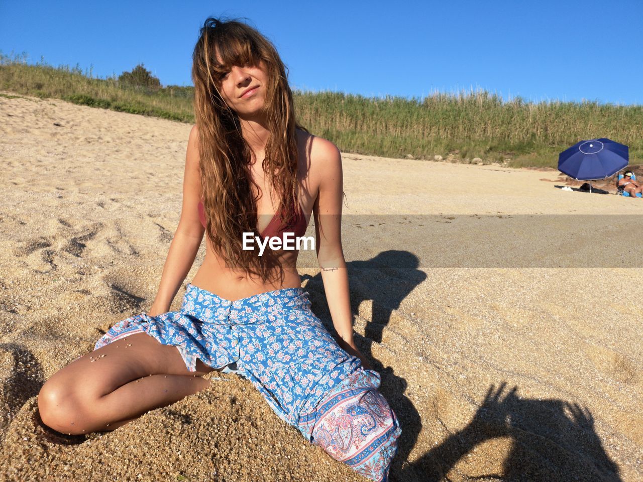 Portrait of beautiful smiling young woman sitting on sand at beach