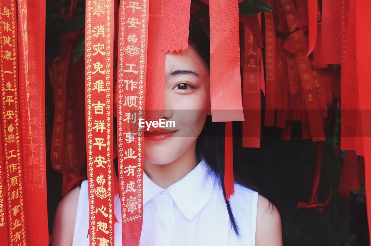 Close-up portrait of young woman amidst red ribbon