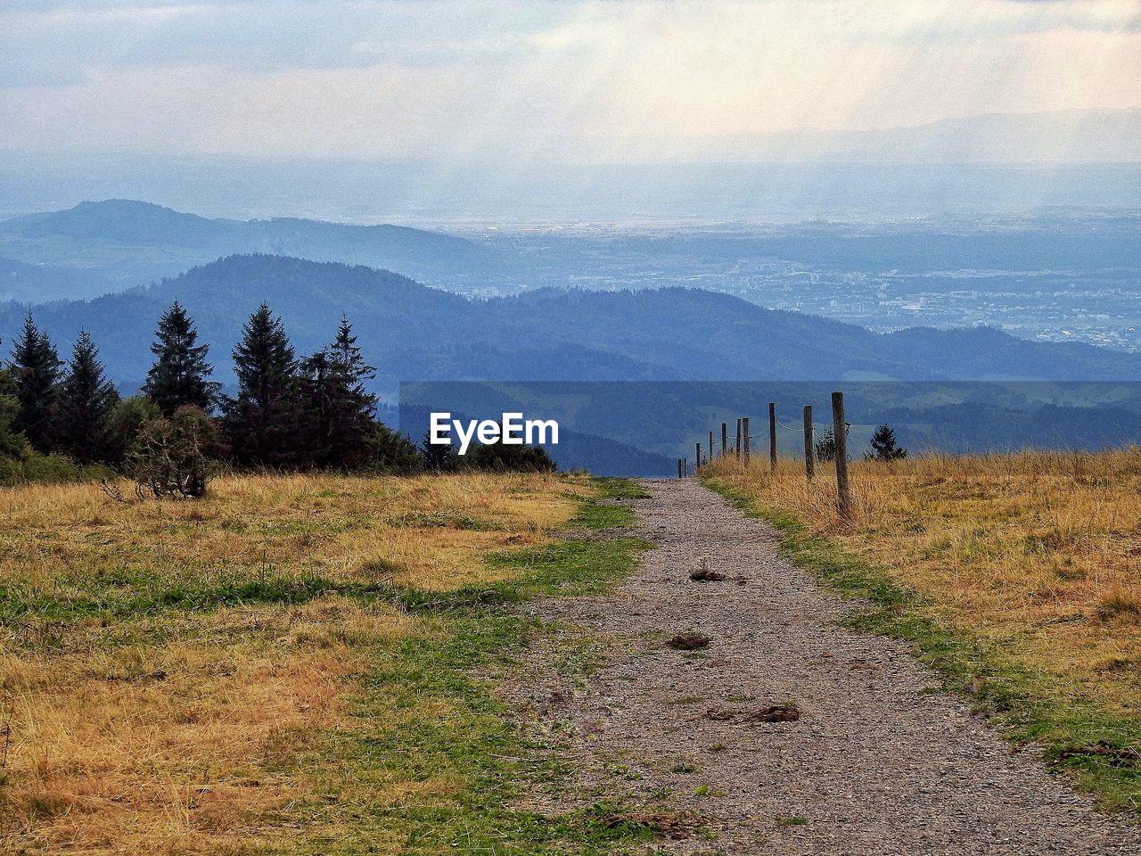 Scenic view of wandering path on top hill against moutain range