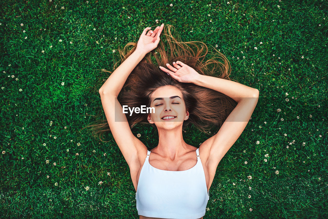 High angle view of smiling young woman lying down on grass