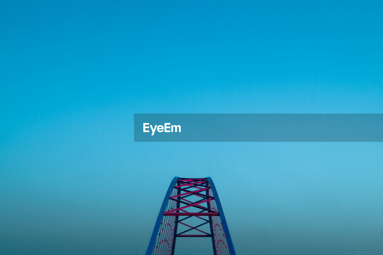 Cropped metallic bridge against clear blue sky