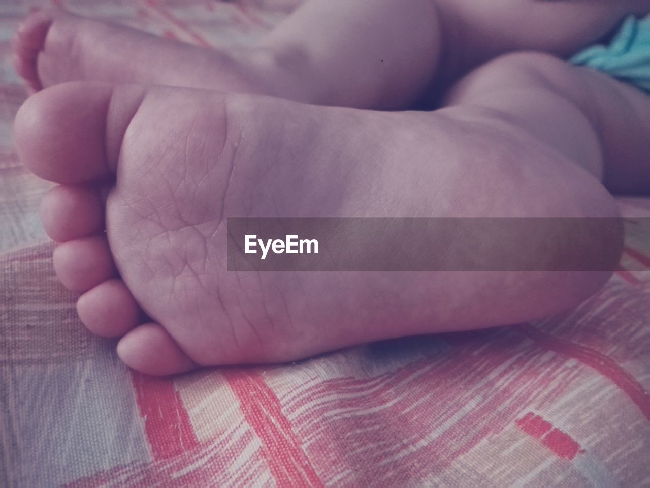 Low section of baby resting on bed