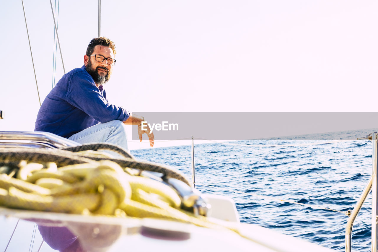 MAN SAILING ON SAILBOAT AGAINST SEA