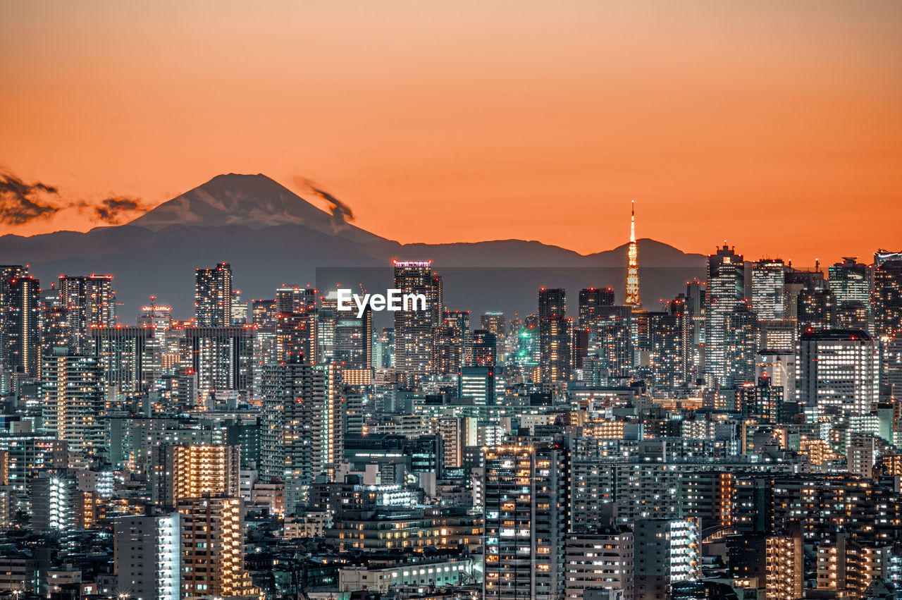 Illuminated buildings in city against sky during sunset