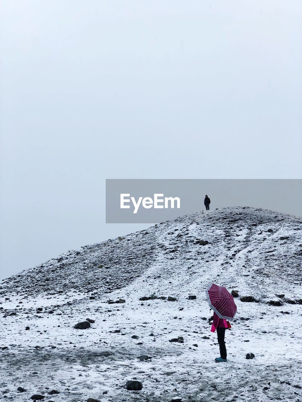 Rear view of people on snow covered land against sky