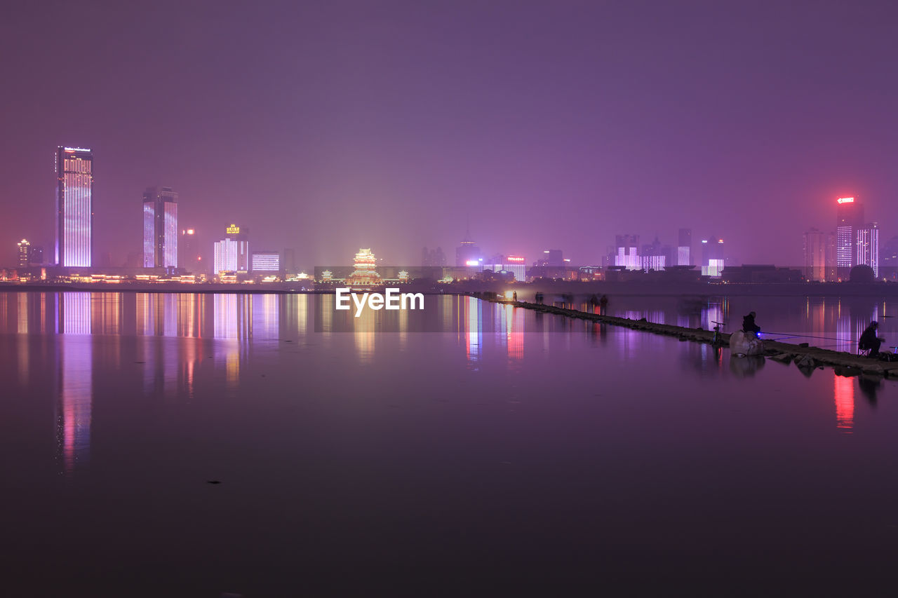 Illuminated skyline reflecting on river at night