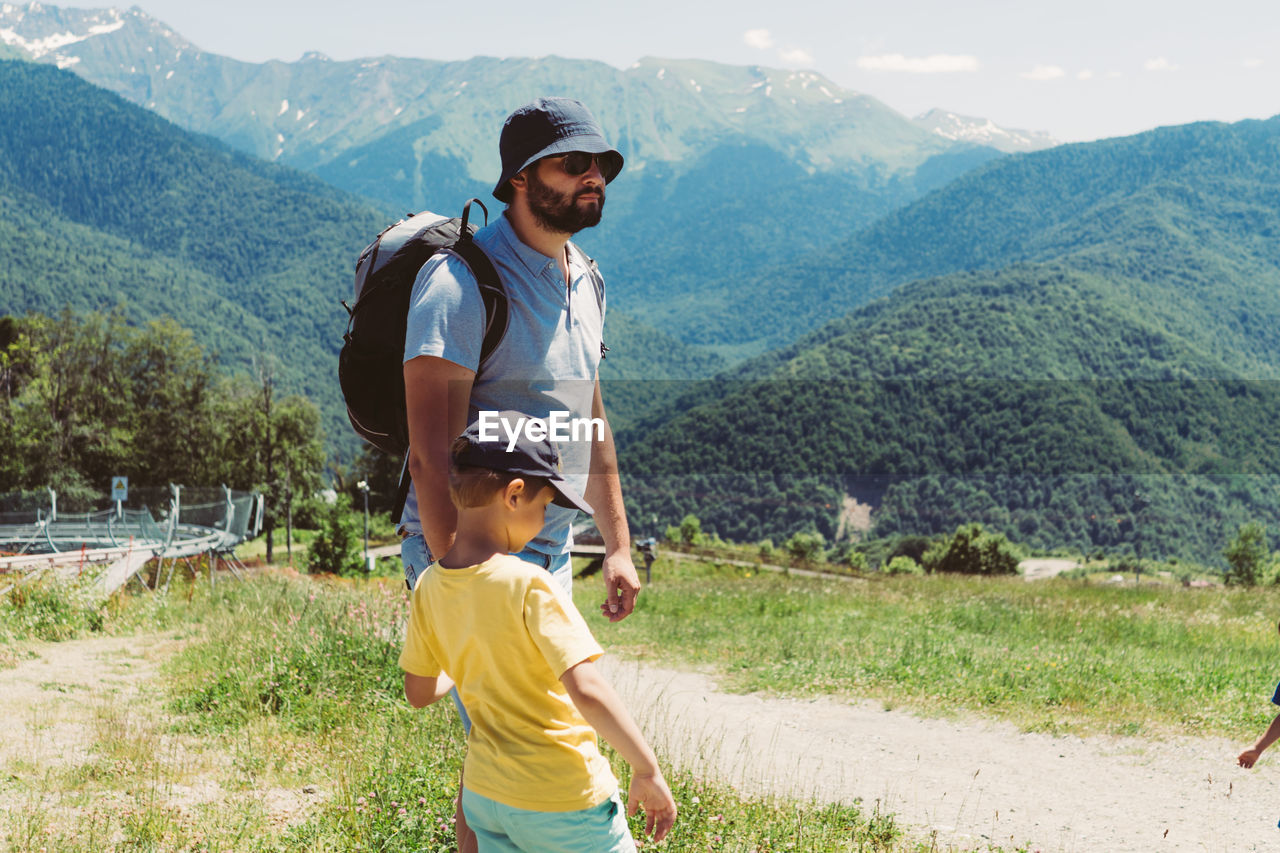 Millenial bearded tourist man hiking in mountains with child. father and son spend time together