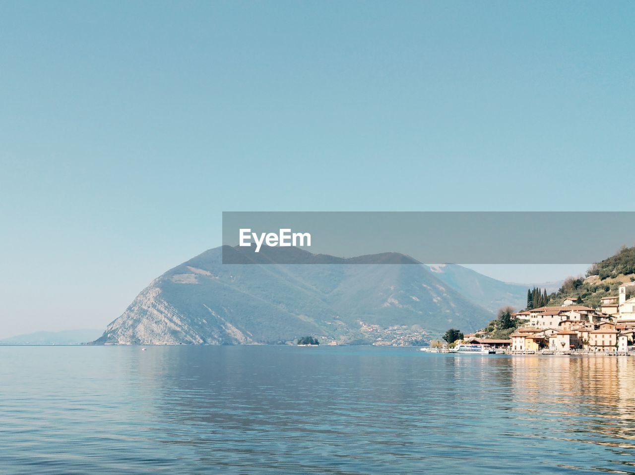 Scenic view of sea and mountains against clear blue sky