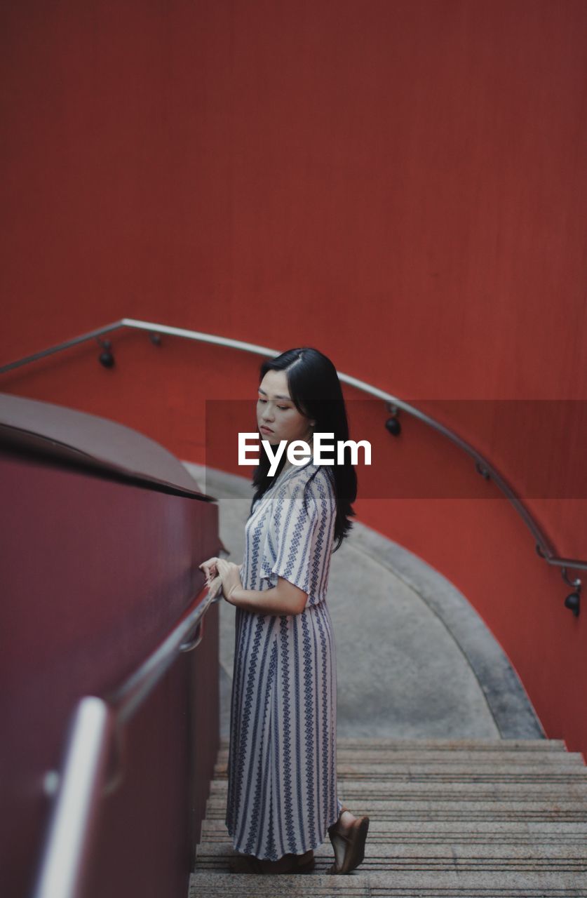 Side view of young woman standing on staircase