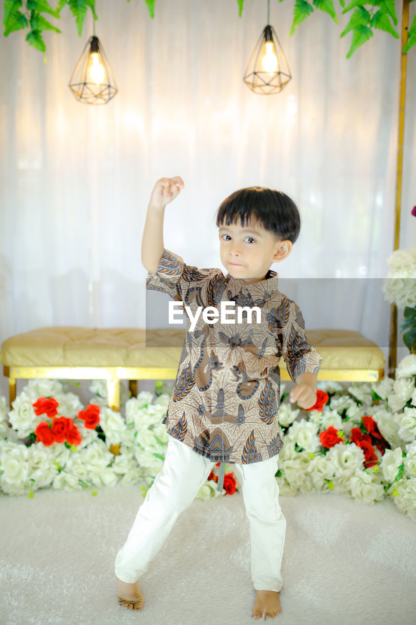 childhood, one person, child, full length, indoors, flower, toddler, cute, plant, baby, portrait, front view, men, nature, floristry, happiness, standing, domestic room, innocence, dress, fun, clothing, emotion, smiling, spring, flowering plant, lifestyles, looking at camera, person, home interior, celebration, casual clothing