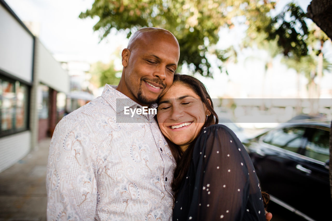 Multiracial late forties couple embracing on san diego sidewalk