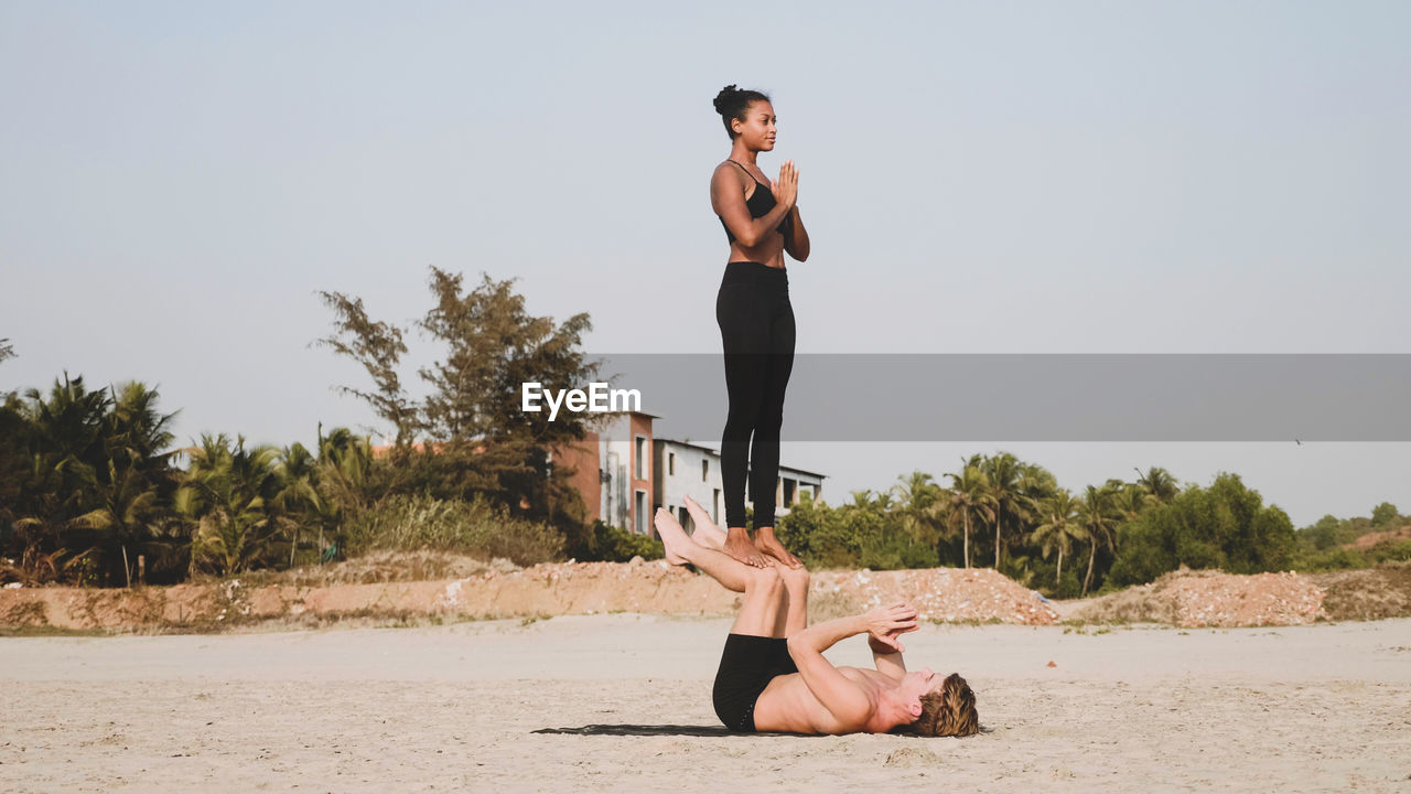 Man and woman doing yoga at beach