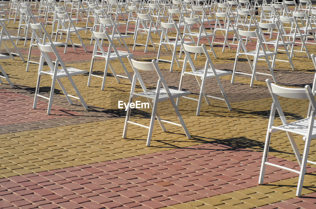 White folding chairs are placed on square on pavement. quarantine, events, a concert on street