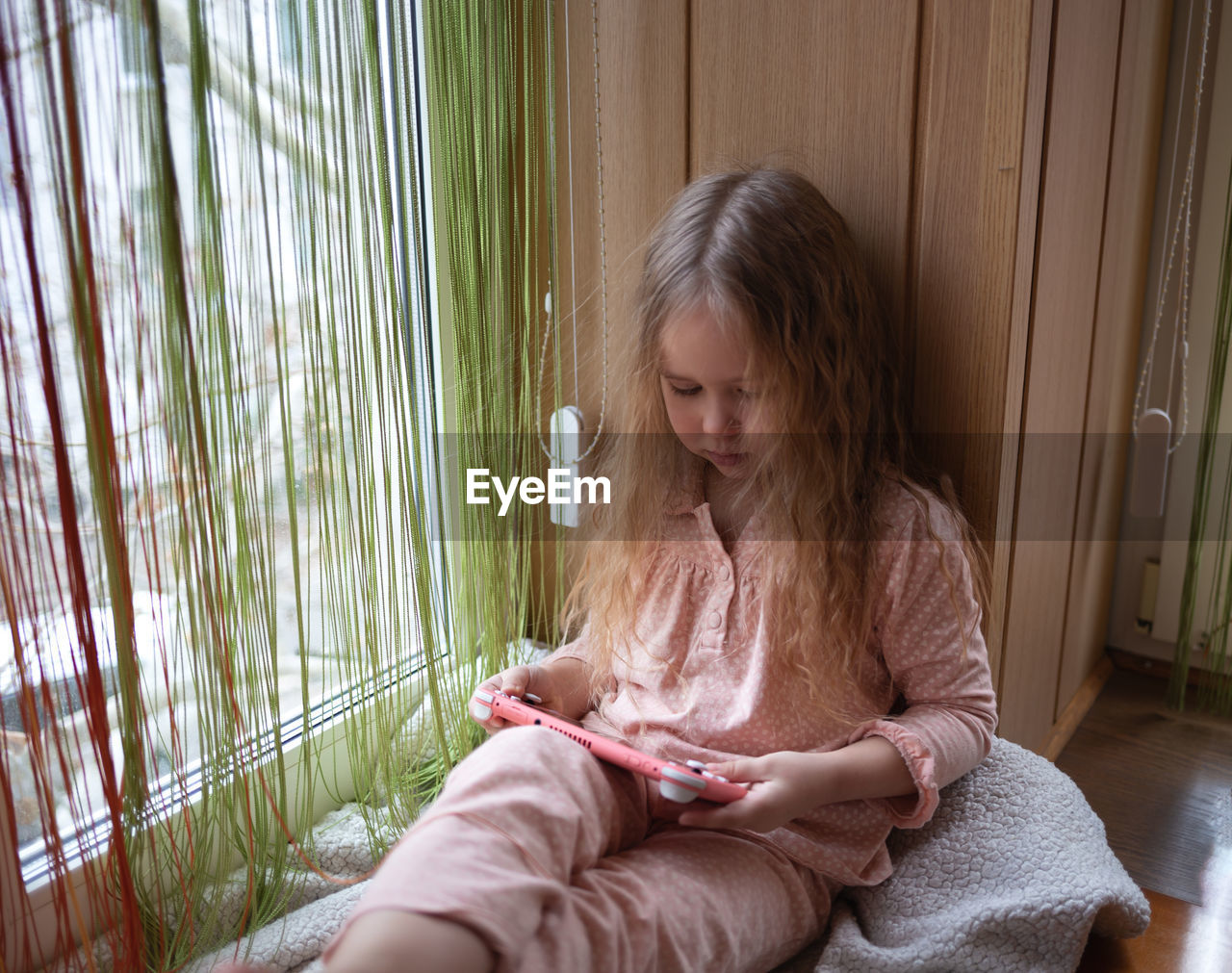 side view of girl looking through window at home