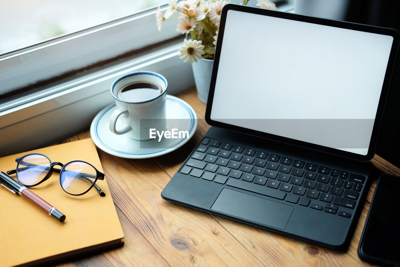 Coffee cup and laptop on table