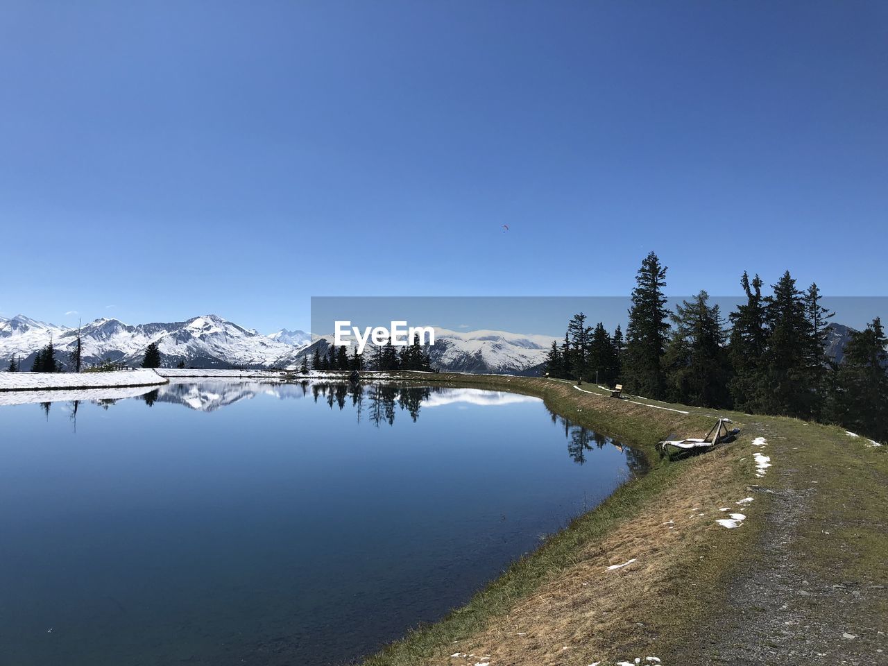 Scenic view of lake by snowcapped mountains against clear blue sky