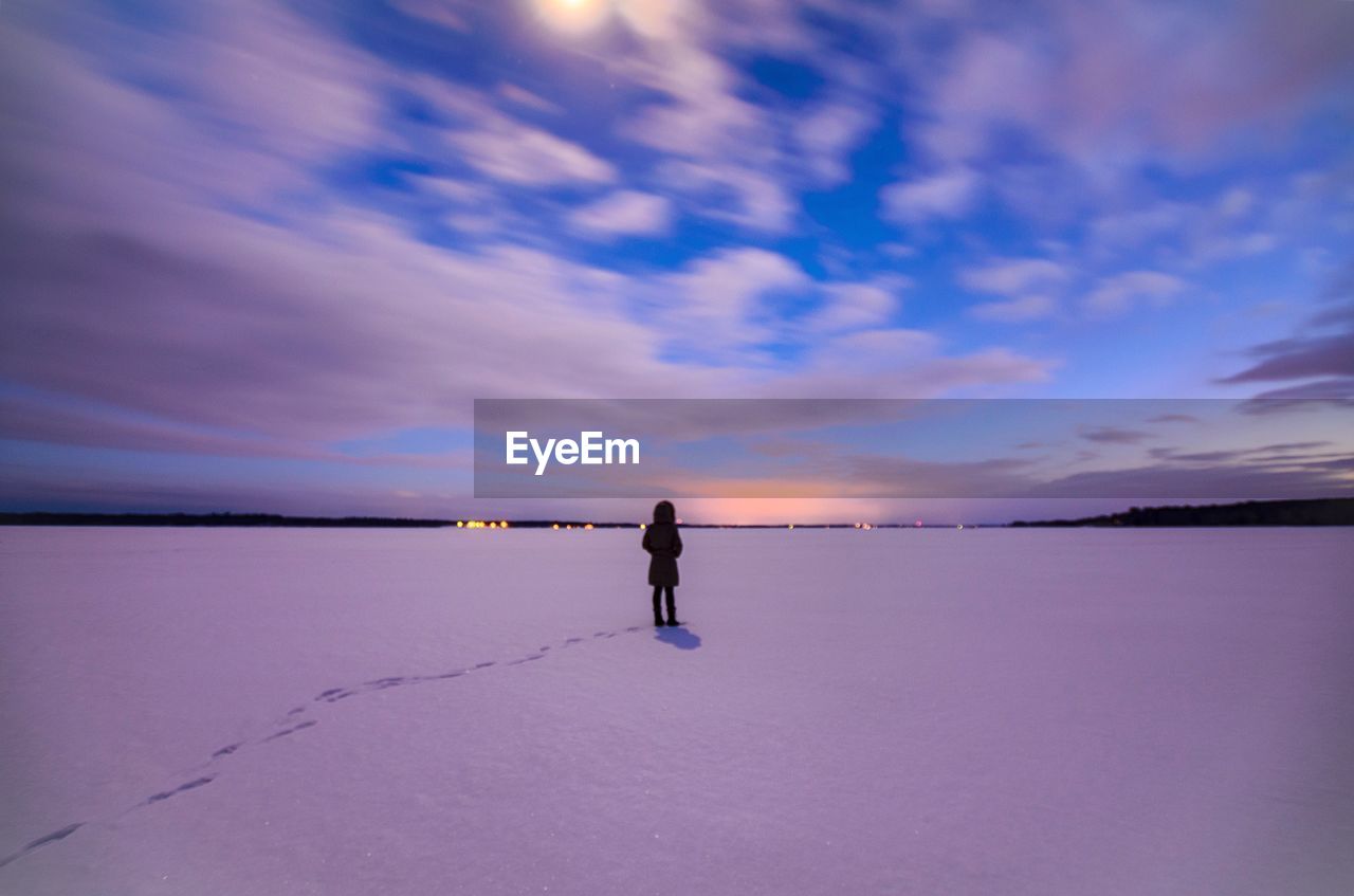 REAR VIEW OF MAN STANDING ON BEACH