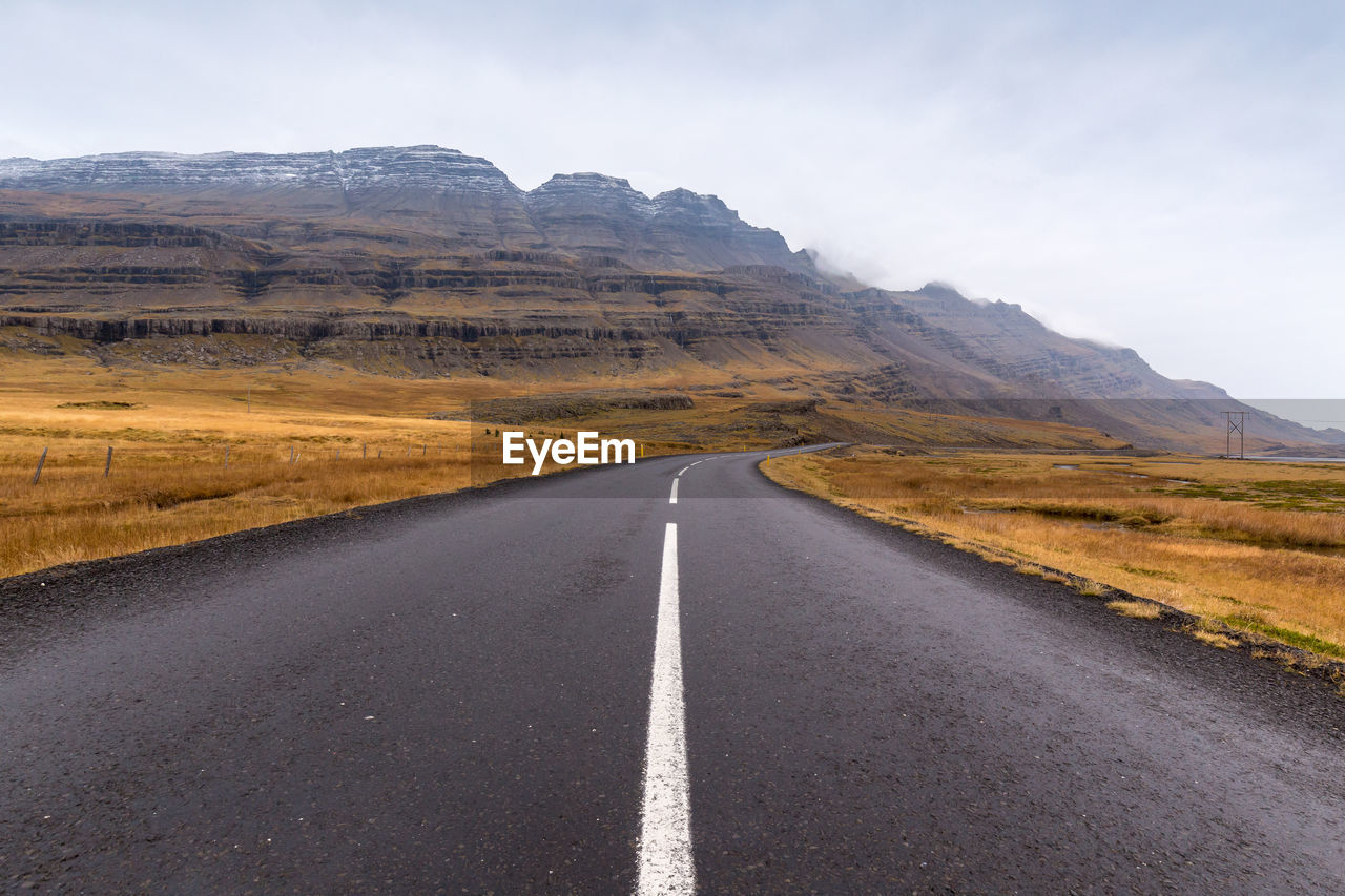 Empty road by mountain against sky