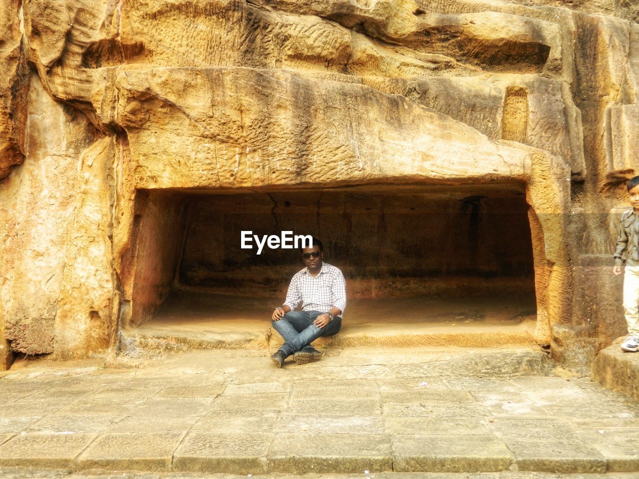 FULL LENGTH OF MAN SITTING ON STONE WALL