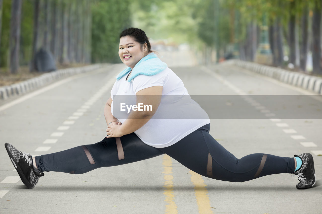 Portrait of smiling young woman exercising on road