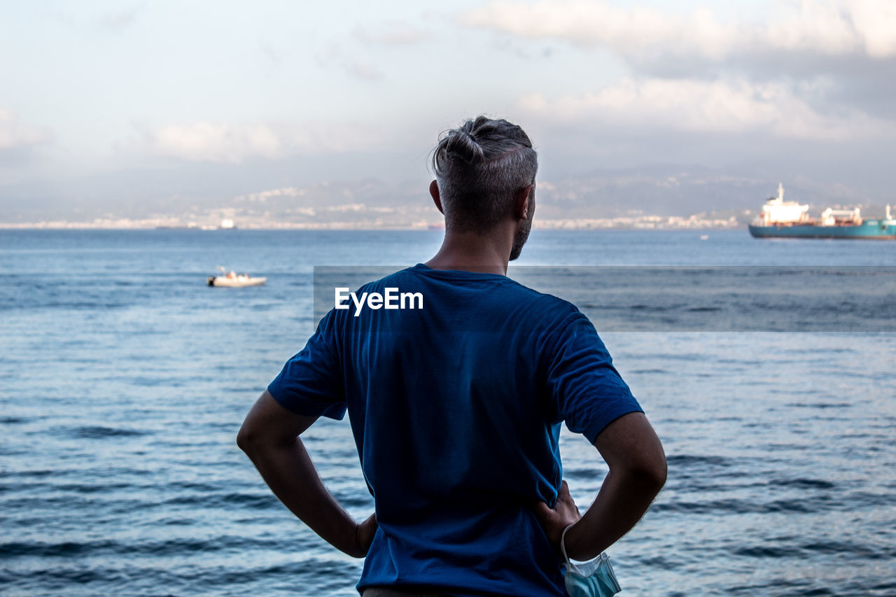 Rear view of man looking at sea against sky