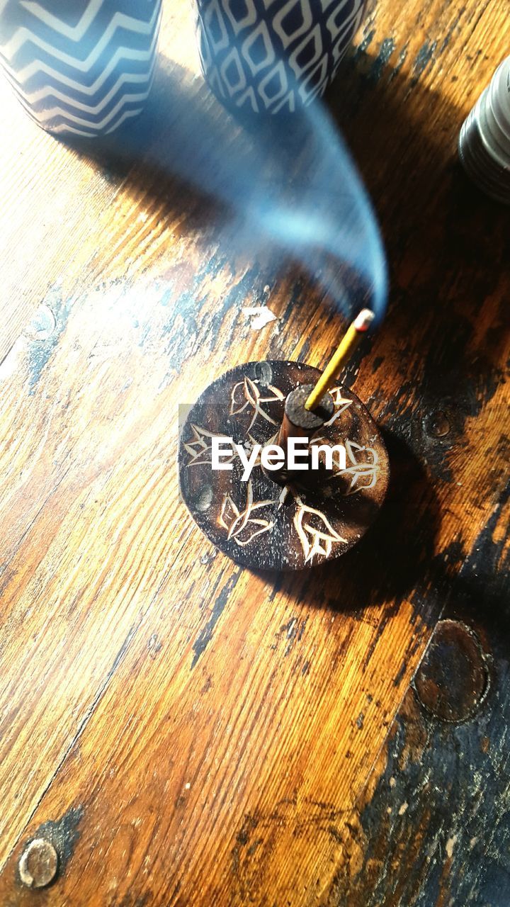 High angle view of burning incense on wooden table