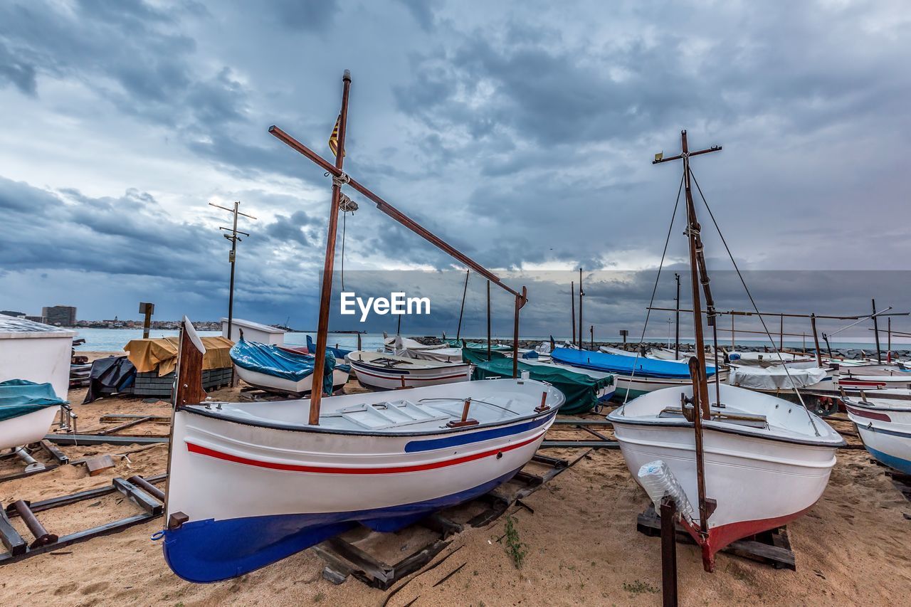 BOATS MOORED ON SHORE AGAINST SKY
