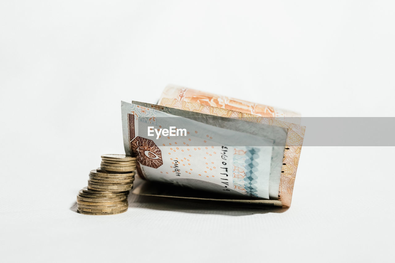 Close-up of coins with paper currencies against white background