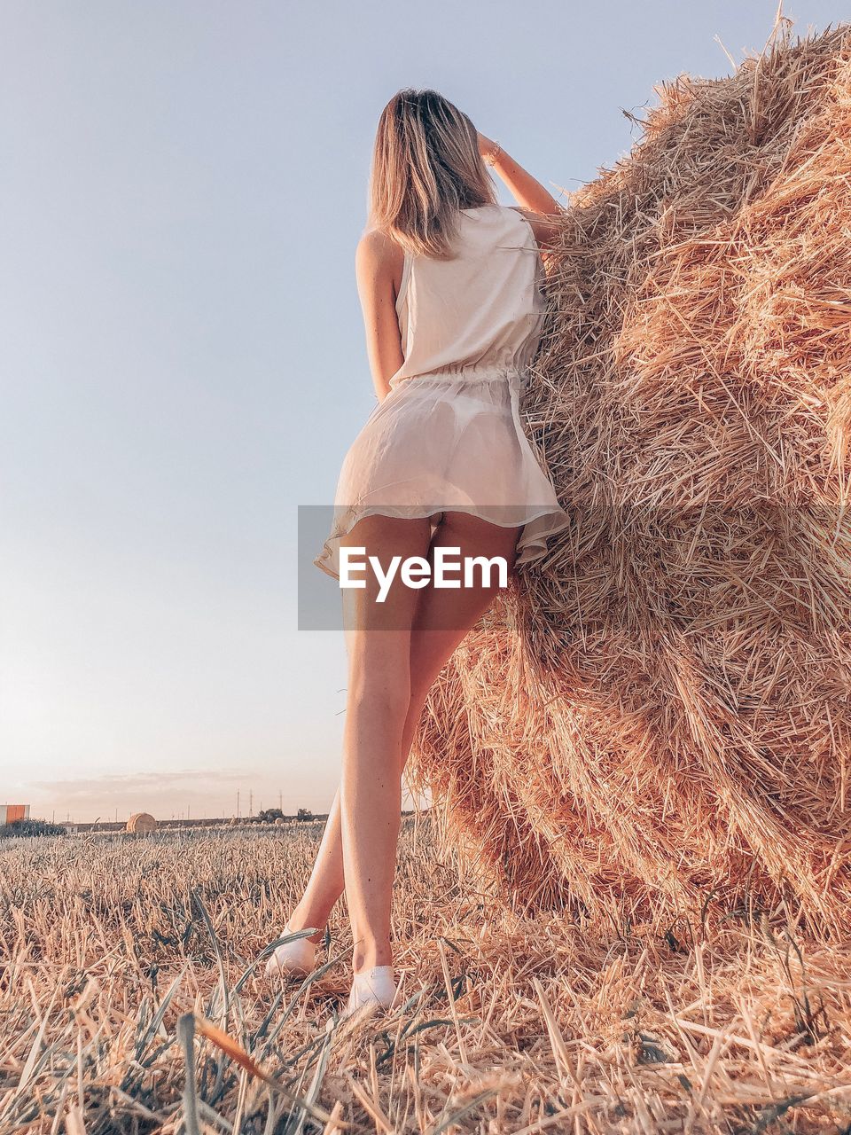 Low angle view of woman standing by hay against sky