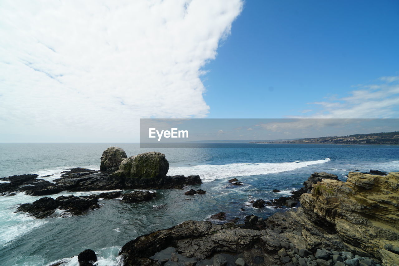 SCENIC VIEW OF ROCKS ON SHORE AGAINST SKY