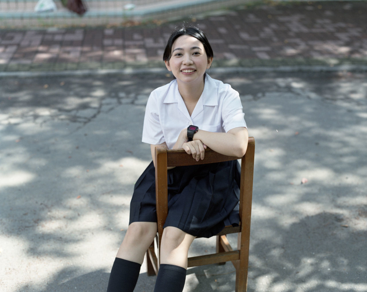 Portrait of happy beautiful woman sitting on chair at street