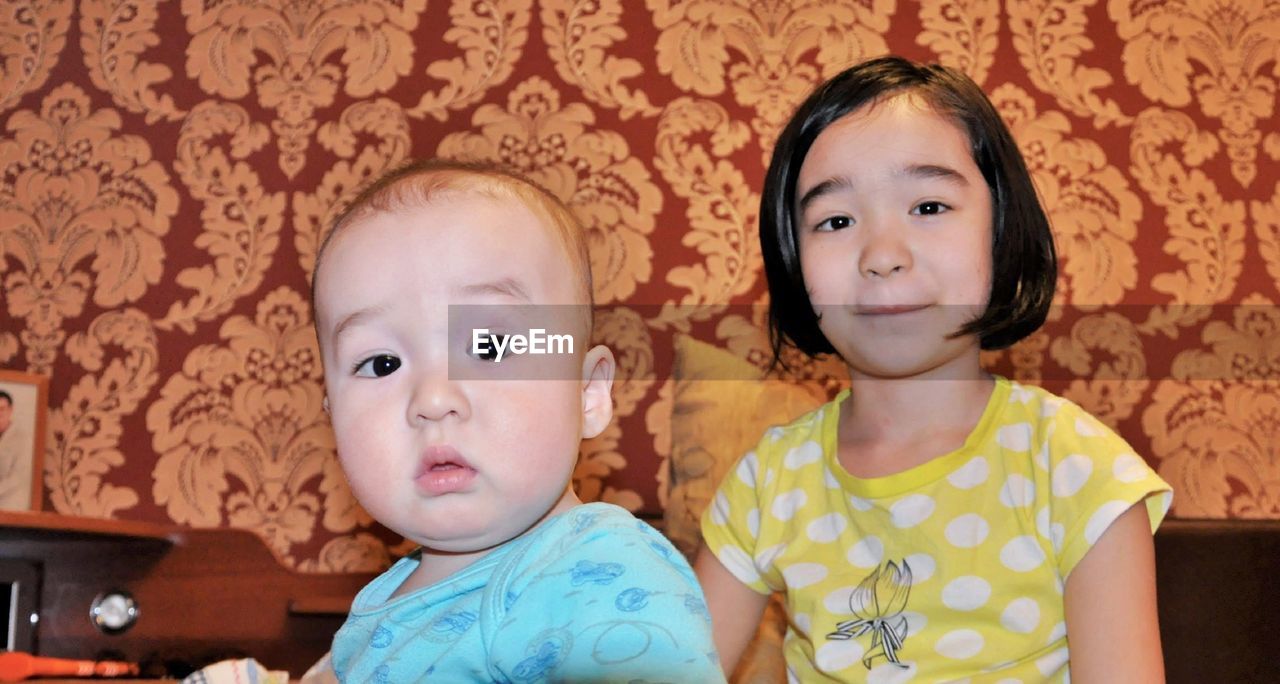 Portrait of cute siblings sitting at home