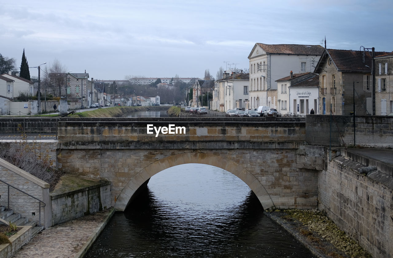 Bridge over river in city against sky