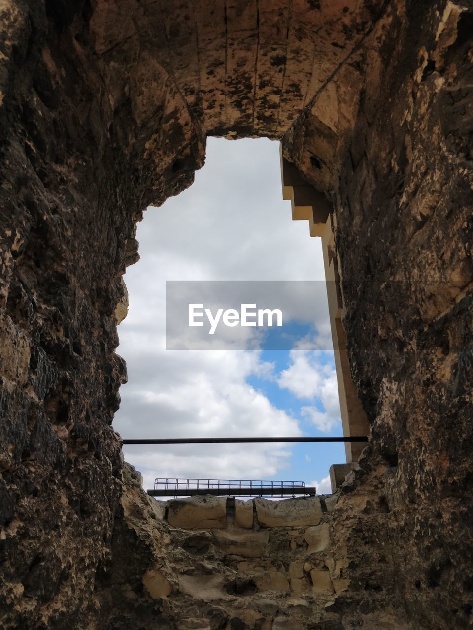 LOW ANGLE VIEW OF HISTORIC BUILDING SEEN THROUGH HOLE IN ROCK