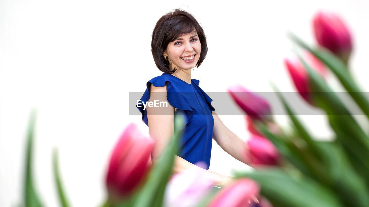 flower, plant, flowering plant, one person, women, smiling, happiness, adult, nature, beauty in nature, freshness, emotion, portrait, tulip, cheerful, female, selective focus, springtime, waist up, spring, growth, young adult, purple, multi colored, anime, looking at camera, indoors, studio shot, clothing, white background, lifestyles, child