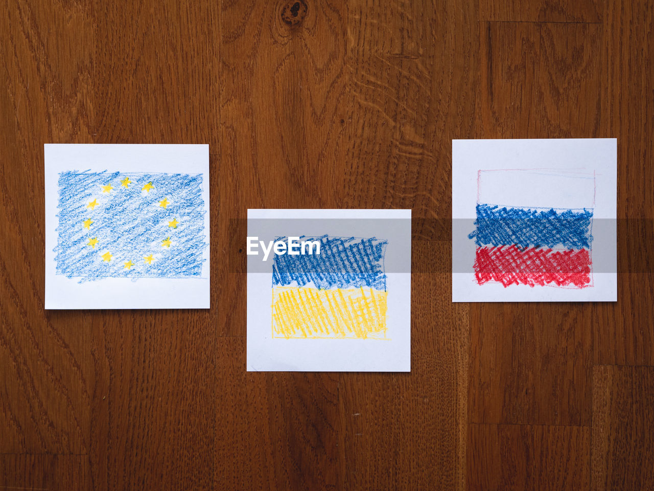 Directly above shot of paper on wooden table with ukrainian european and russian flags