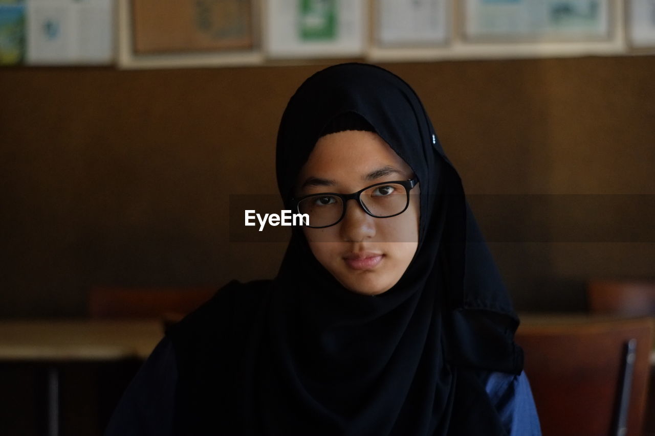 Portrait of girl wearing hijab and eyeglasses at restaurant