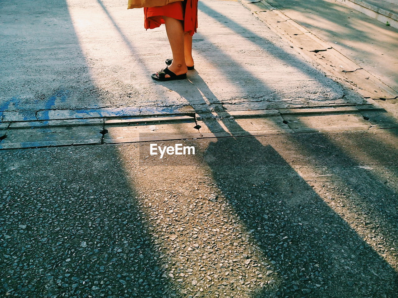 Low section of woman standing on footpath