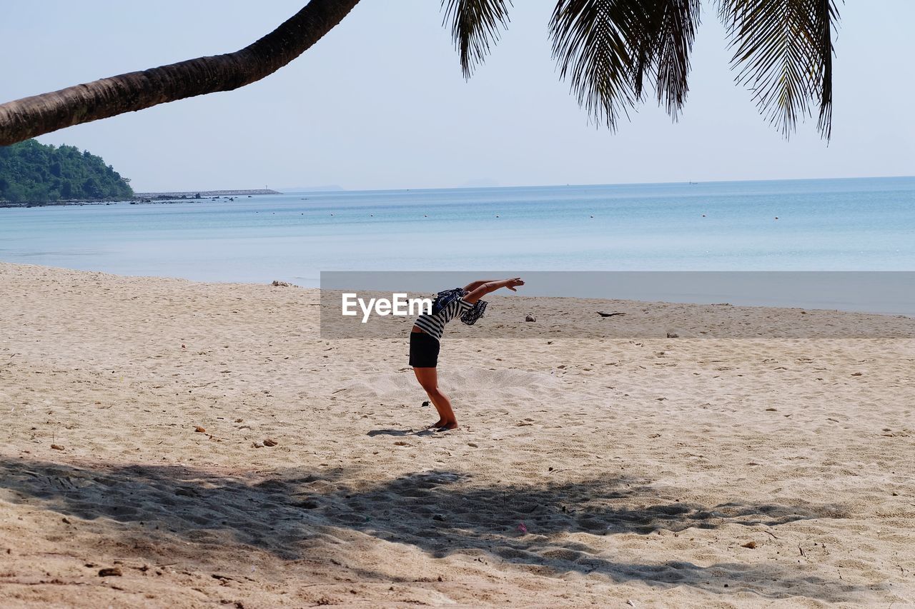 WOMAN ON BEACH AGAINST SKY