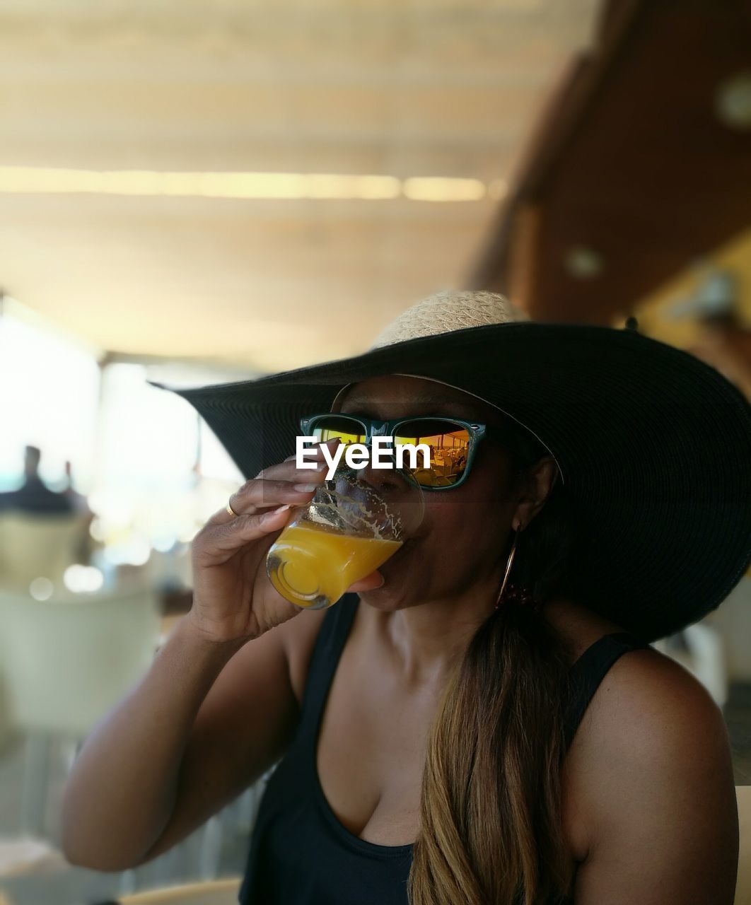 Woman wearing hat drinking juice at restaurant